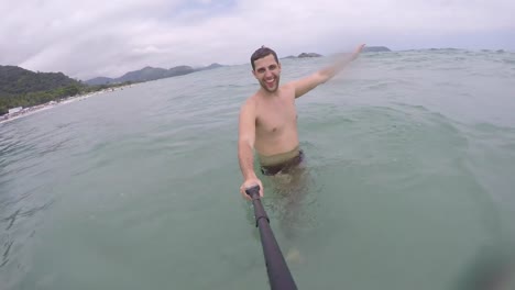 Chico-brasileño-joven-divirtiéndose-y-teniendo-un-selfie-en-la-playa