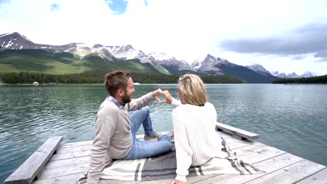 Joven-pareja-haciendo-forma-marco-de-corazón-en-el-paisaje-de-montaña-lake,-Canadá