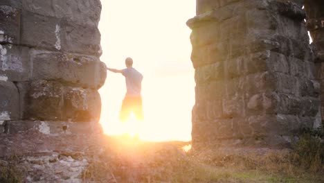 Junger-Mann-in-der-Sportswear-Dehnung-unter-antike-römische-Aquädukt-Appio-Claudio-Arch.-Trainieren-im-Freien-in-ruhigen-Park-in-Rom-bei-Sonnenuntergang-Slow-motion