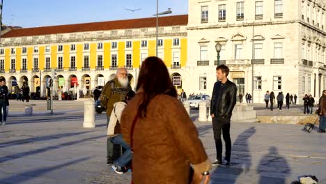 Guitarrista-tocando-una-canción-con-una-guitarra-y-la-gente-escucha-la-música-en-el-Terreiro-Paço-Praça-do-Comércio