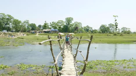 Girl-walks-along-the-wooden-bridge-through-the-river,-asia,-Nepal.