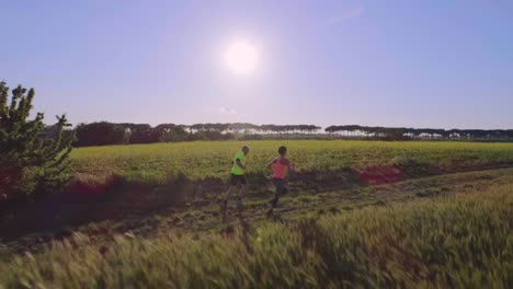 Pareja-joven-para-correr-en-el-campo-cerca-del-bosque-al-atardecer