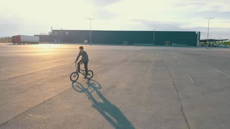 fliegende-Kamera-Junge-männliche-Jugendliche-Reiter-auf-dem-bmx-Rad-auf-der-leeren-städtischen-Stelle,-die-keine-Menschen-asphalt