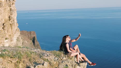 Side-view-active-tourist-couple-posing-taking-selfie-using-smartphone-on-edge-cliff-break