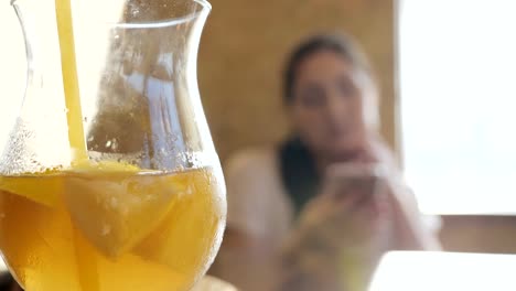 Glass-glass-with-a-cocktail-and-straw-on-the-background-of-a-young-woman