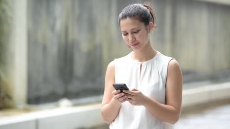 Porträt-von-schönen-jungen-glücklich-Frau-im-Freien-mit-Handy