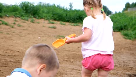 Little-girl-picks-up-and-pours-water-out-of-the-bucket-into-the-sand-closeup.-Child-playing-on-the-beach.