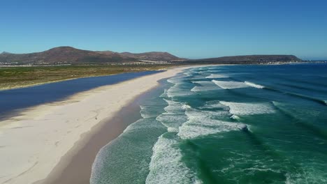 Aerial-view-of-a-long-beach,-people-and-the-ocean