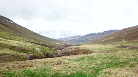 Stunning-drone-view-of-woman-standing-arms-outstretched-on-top-of-canyon-in-Iceland