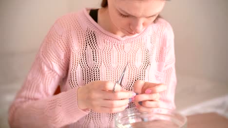 Mujer-corta-con-tijera-y-pinza-de-la-cutícula.-Hace-manicura-a-sí-misma.-Herramientas-sobre-la-mesa-de-manicura