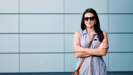 Hübsche-junge-Frau-in-Sonnenbrille-steht-mit-verschränkten-Armen