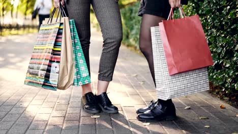 Ángulo-bajo-la-foto-de-mujeres-piernas-de-pie-en-la-acera-con-bolsas-de-la-compra-después-de-feliz-día-en-tiendas-y-centros-comerciales.-Concepto-de-personas,-el-consumismo-y-el-ocio.