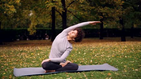 Slender-girl-is-doing-yoga-exercises-for-healthy-spine-stretching-body-and-arms-then-relaxing-in-lotus-position-with-hands-on-kness-and-closed-eyes.-Youth-and-meditation-concept.