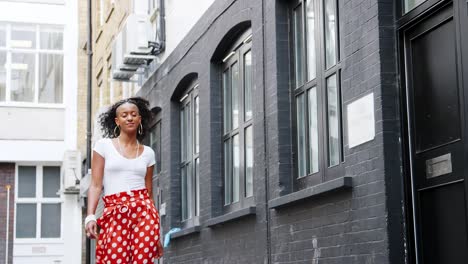 Moda-joven-mujer-negro-pantalones-de-lunares-rojo-paseando-por-un-calle,-bajo-ángulo