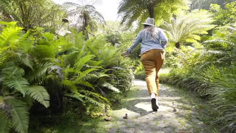 Mujer-caminando-en-el-sendero-entre-las-plantas-verdes