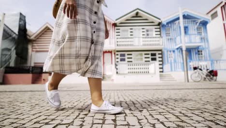 Crop-woman-walking-near-colorful-buildings