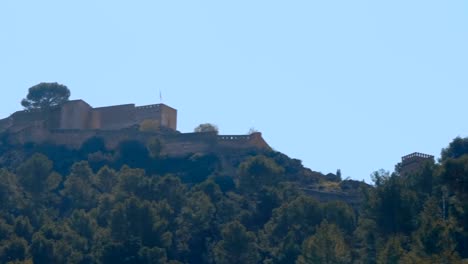 Castillo-medieval-en-la-cima-de-una-montaña-arbolada-en-la-España