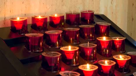 Rows-of-burning-candles-in-red-forms-in-a-church-in-Spain