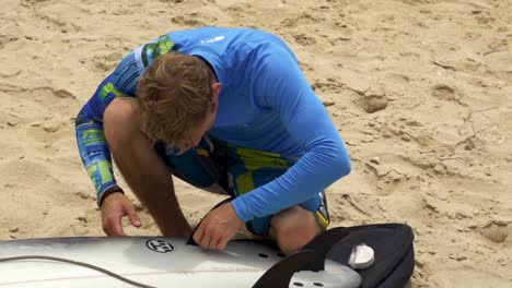 Young-surfer-inserting-fins-into-the-surfboard