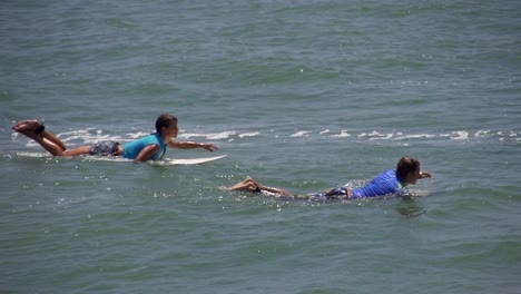 SLOW-MOTION:-Surfer-boy-and-girl-paddling