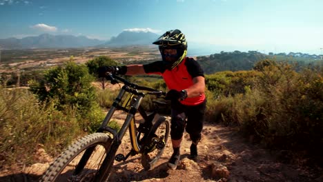 Mountain-biker-pushing-his-bike-over-rough-terrain