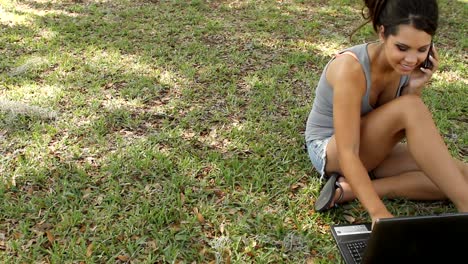 Hübsche-student-auf-Handy-und-laptop-im-park
