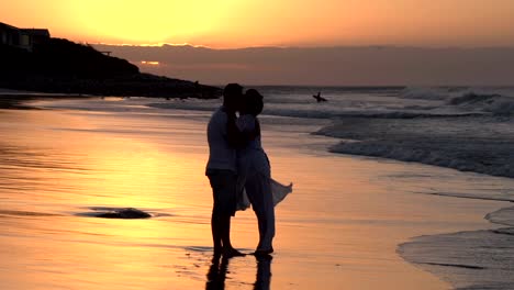 Couple-enjoying-romantic-embrace-on-the-beach-in-silhouette,South-Africa