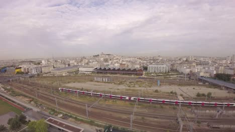 Paris,-10.-Arrondissement-–-Luftbild-von-TGV-high-speed-Zug-vorbei-am-Bahnhof-Gare-Du-Nord-in-Halle-Pajol-und-die-Skyline-der-Stadt-im-Hintergrund.