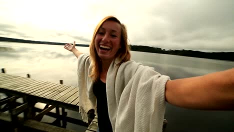 Mujer-joven-en-muelle-de-madera-sobre-el-lago,-toma-selfie-retrato