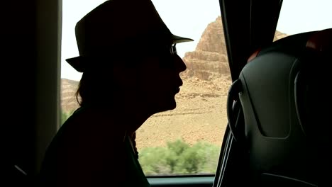 Young-woman-looking-trough-the-window-and-playing-with-hands-sitting-on-backseats-in-bus-during-road-trip