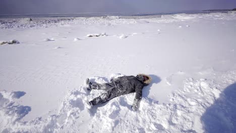 Boy-hacer-de-Ángel-de-nieve-ontario-Canadá-en-invierno-con-nieve