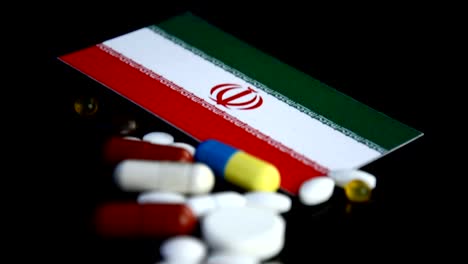 Bandera-iraní-con-gran-cantidad-de-píldoras-médicas-aisladas-sobre-fondo-negro