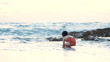 Niña-jugando-en-la-playa-en-el-agua-durante-la-hora-del-atardecer