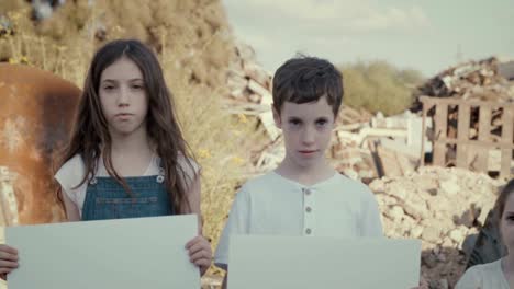 Save-the-planet.-young-kids-holding-signs-standing-in-a-huge-junkyard