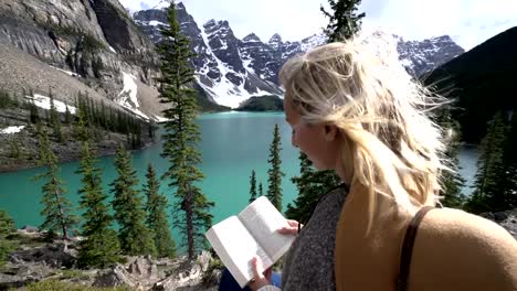 Libro-de-lectura-de-mujer-joven-en-el-lago-de-la-montaña