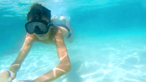 Niños-bajo-el-agua-nadan-hacia-cámara-con-máscaras-de-snorkel