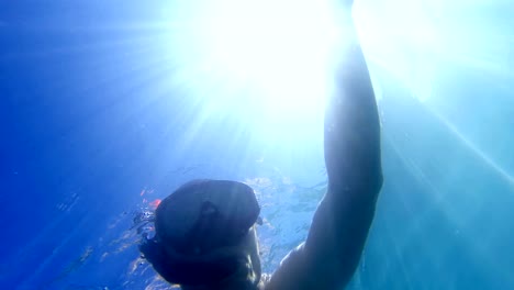 Young-man-snorkeling-with-sunrays-view-from-bellow,-uhd-shoot