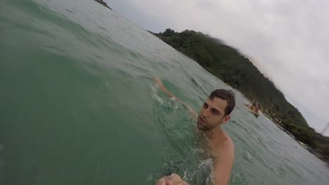 Chico-brasileño-joven-divirtiéndose-y-teniendo-un-selfie-en-la-playa