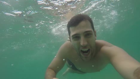 Chico-brasileño-joven-divirtiéndose-y-teniendo-un-selfie-en-la-playa