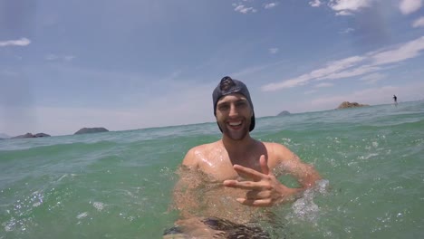 Junge-brasilianische-Kerl-Spaß-haben-und-dabei-eine-Selfie-am-Strand