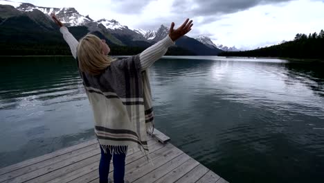 Young-woman-arms-outstretched-on-lake-pier-,-Canada
