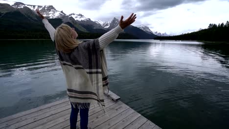 Brazos-de-la-joven-extendidos-en-el-muelle-del-lago,-Canadá