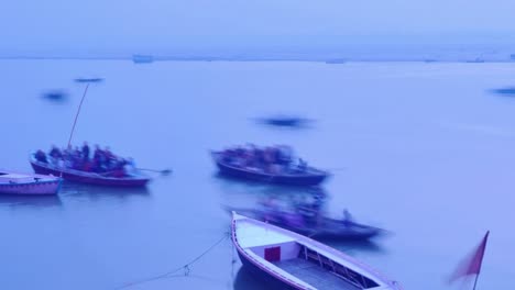 Indian-pilgrims-rowing-boat-in-dawn,-Ganges-river-in-Varanasi,-India.