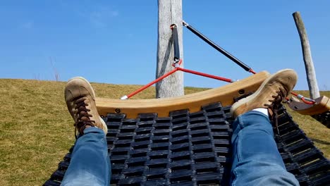 Male-tourist-swinging-in-hammock,-lazy-free-time,-refreshment-on-peaceful-meadow