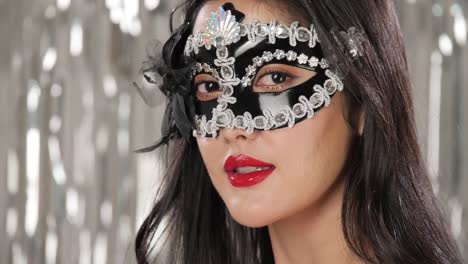 Sexy-woman-wearing-masquerade-mask-flirting-at-party-over-silver-glitter-background,-slow-motion