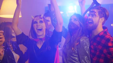 Funny-friends-in-costumes-dancing-at-night-halloween-party