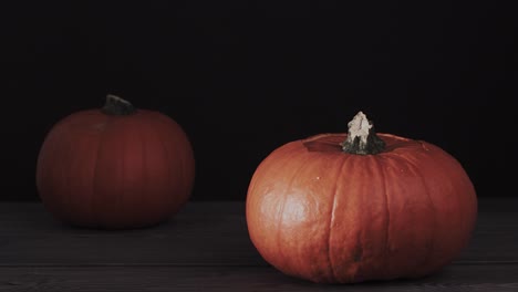 Dos-calabazas-de-halloween-con-cara-de-miedo-en-la-mesa-de-madera