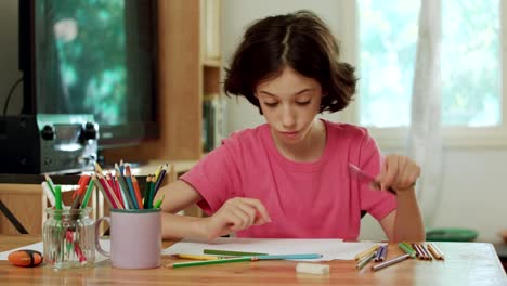 young-girl-sitting-at-the-table-drawing-with-colored-pencils