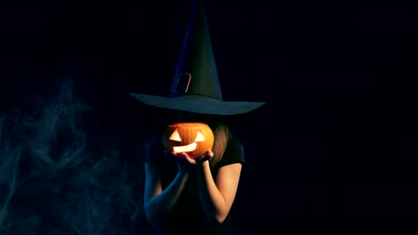 Girl-wearing-black-witch-hat-holding-jack-o'-lanterns