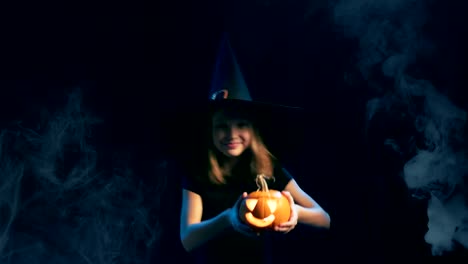 Girl-wearing-black-witch-hat-holding-jack-o'-lanterns